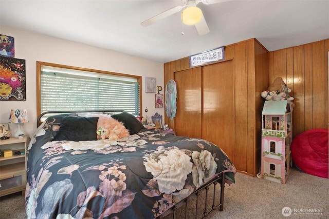bedroom featuring wooden walls, a closet, carpet flooring, and ceiling fan
