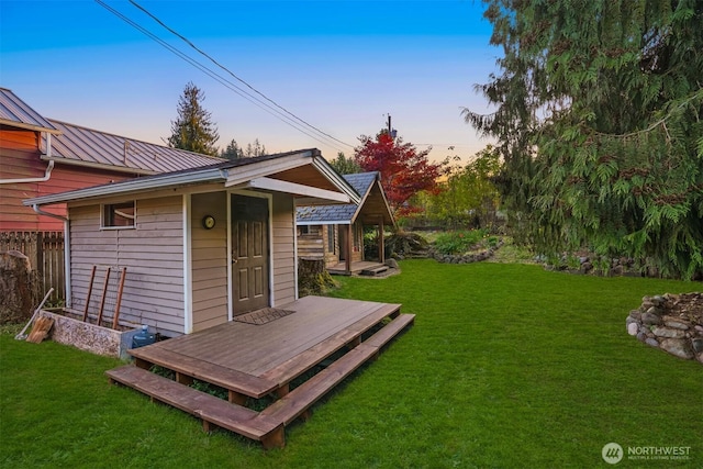 exterior space with a wooden deck, an outbuilding, a yard, and metal roof