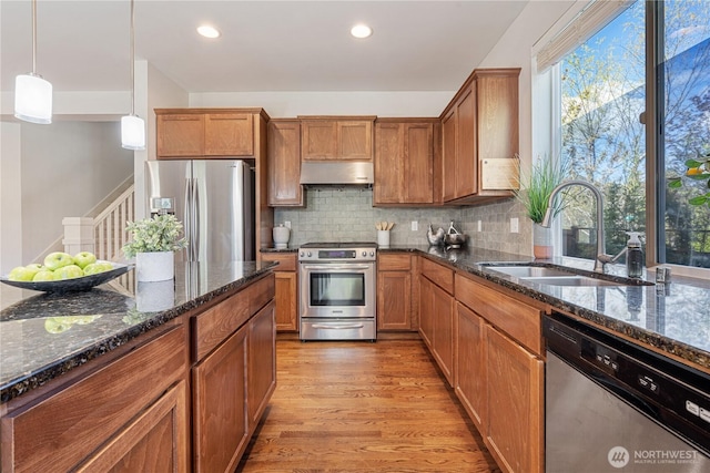10788 243rd Ave NE, Redmond, WA 98053 - kitchen with appliances with stainless steel finishes, a sink, brown cabinetry, light wood finished floors, and tasteful backsplash