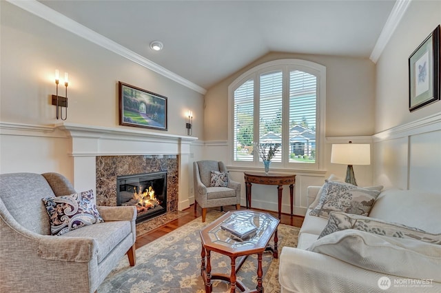 living area featuring crown molding, wood finished floors, lofted ceiling, and a high end fireplace