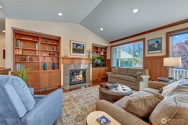 living room with vaulted ceiling, wood finished floors, a wealth of natural light, and built in shelves