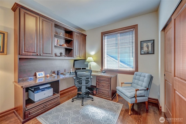 office space with built in desk, baseboards, and wood finished floors