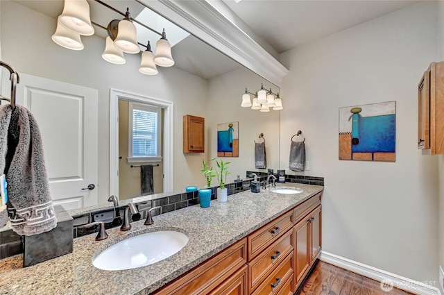 full bath featuring double vanity, a sink, baseboards, and wood finished floors