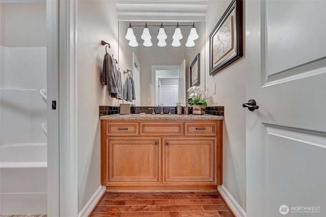 full bathroom featuring a bathing tub, baseboards, wood finished floors, and vanity