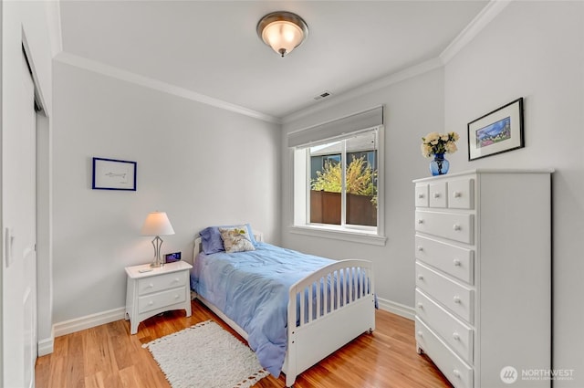 bedroom with crown molding, baseboards, light wood-style flooring, and visible vents