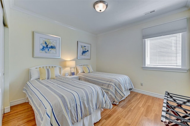 bedroom featuring crown molding, baseboards, wood finished floors, and visible vents