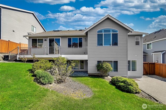 rear view of property with a lawn, a deck, fence, and a patio