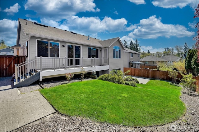 rear view of house featuring a lawn, a fenced backyard, roof with shingles, and a wooden deck