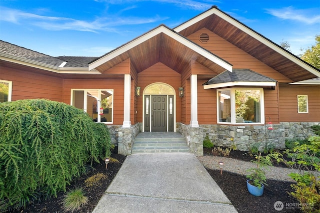 property entrance featuring stone siding and a shingled roof