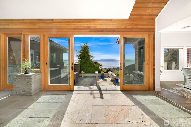 entryway featuring wood walls, stone tile floors, and visible vents