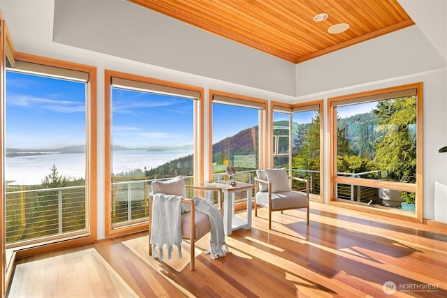sunroom featuring wood ceiling, wood finished floors, a mountain view, and crown molding