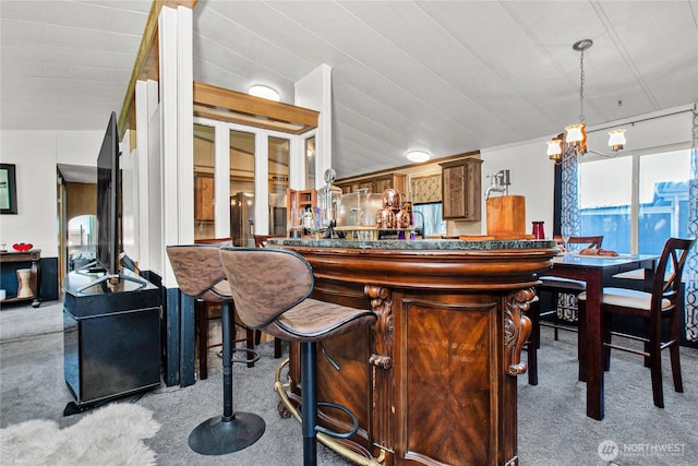 bar with carpet floors, hanging light fixtures, and a bar
