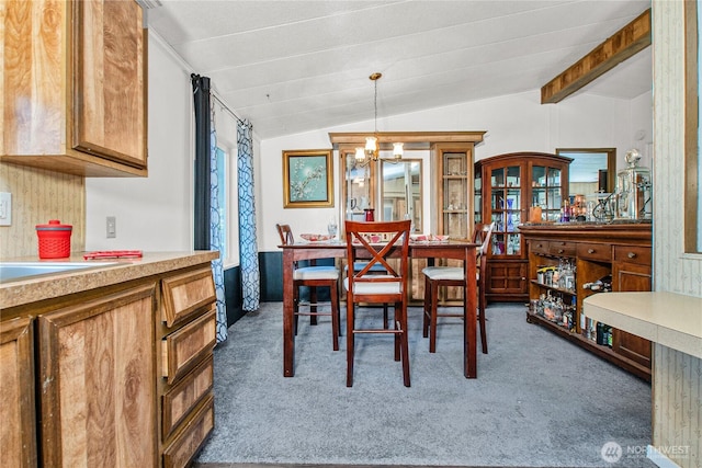 carpeted dining space featuring a notable chandelier and vaulted ceiling