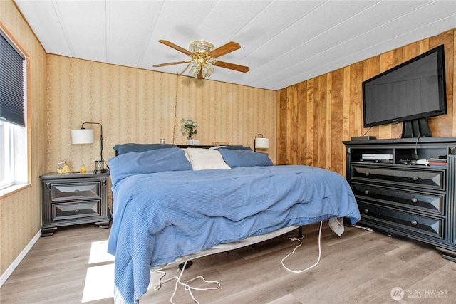bedroom with ceiling fan, wood finished floors, and wallpapered walls