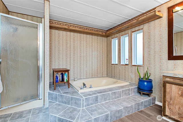 bathroom with a garden tub, a stall shower, wood finished floors, vanity, and wallpapered walls