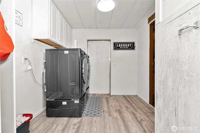 clothes washing area with light wood-style flooring, cabinet space, and washing machine and clothes dryer