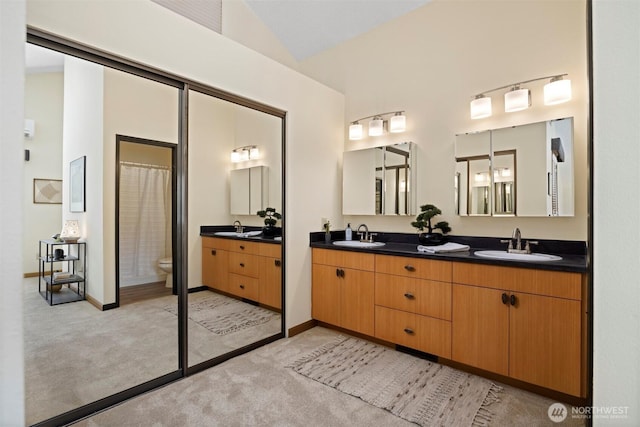 full bath with double vanity, vaulted ceiling, toilet, baseboards, and curtained shower