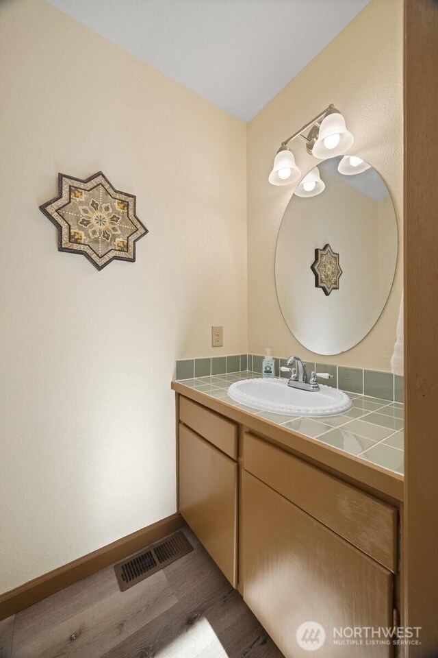 bathroom featuring vanity, wood finished floors, and baseboards