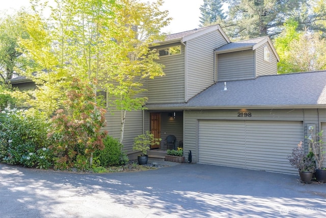 view of front facade featuring an attached garage, asphalt driveway, and a shingled roof