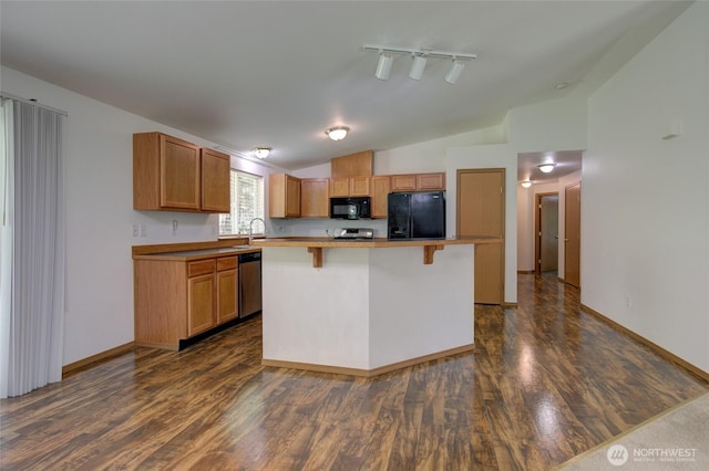 kitchen featuring lofted ceiling, a kitchen breakfast bar, a center island, black appliances, and dark wood-style flooring