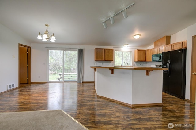 kitchen with a kitchen breakfast bar, dark wood-style floors, visible vents, a chandelier, and black appliances