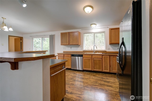 kitchen featuring a kitchen breakfast bar, a sink, dark wood finished floors, freestanding refrigerator, and dishwasher