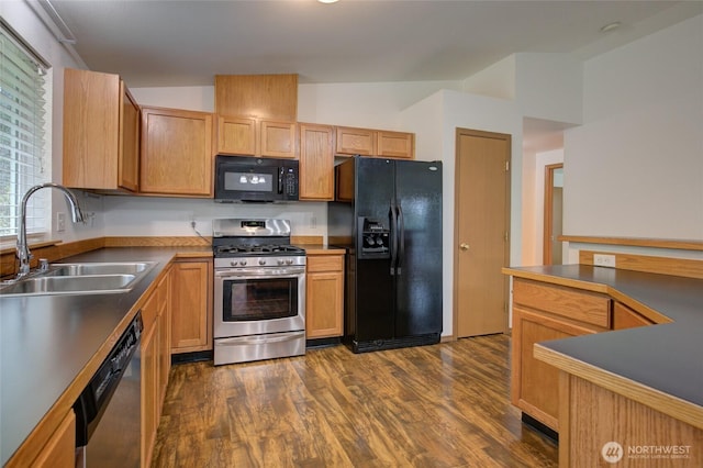 kitchen featuring dark countertops, a sink, dark wood-type flooring, and black appliances