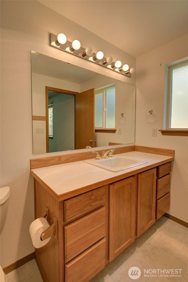 bathroom with toilet, vanity, and baseboards