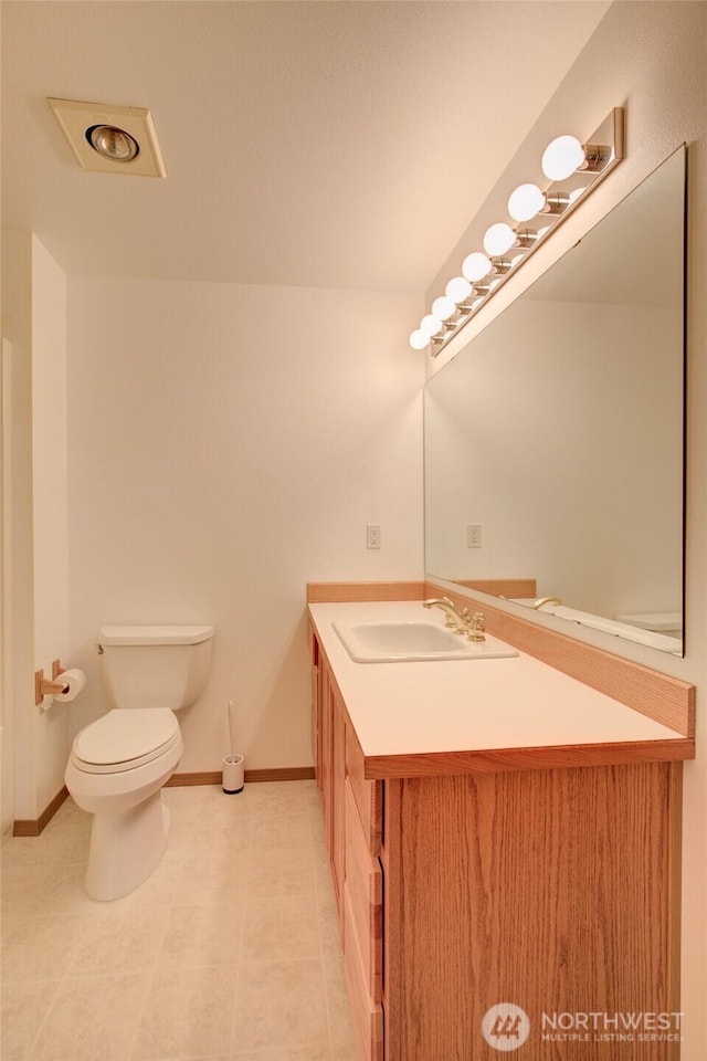 bathroom featuring baseboards, vanity, and toilet
