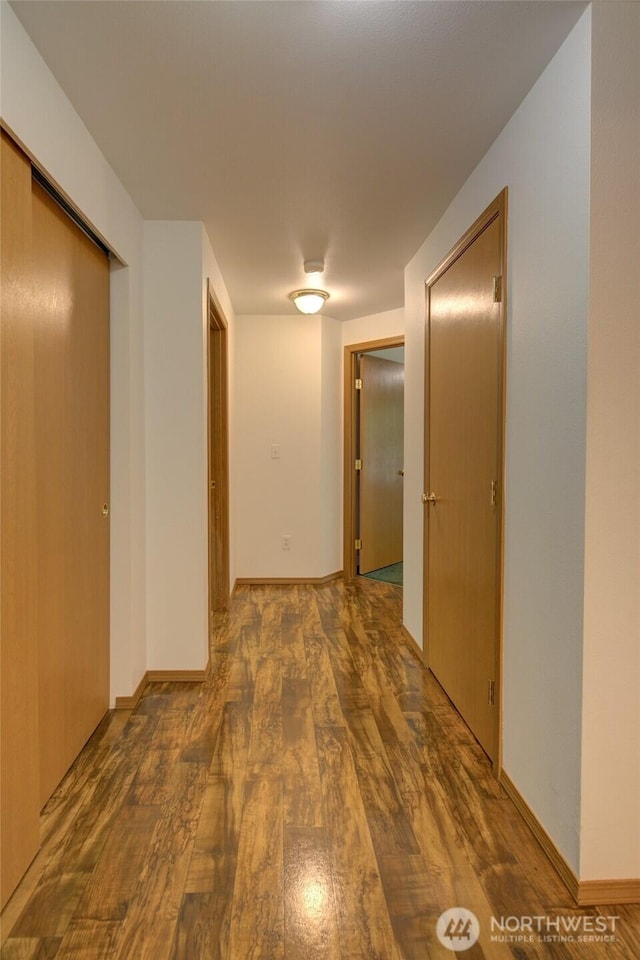 hallway with baseboards and wood finished floors