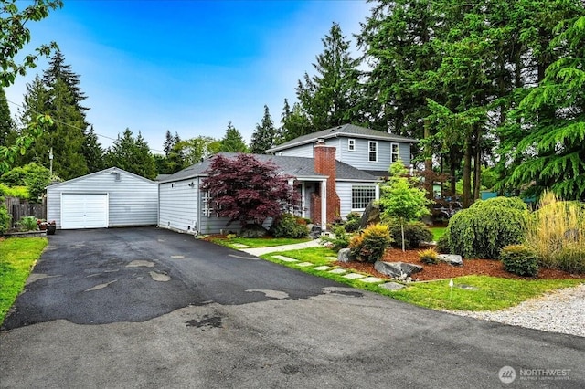 view of front facade featuring a garage, an outbuilding, and driveway