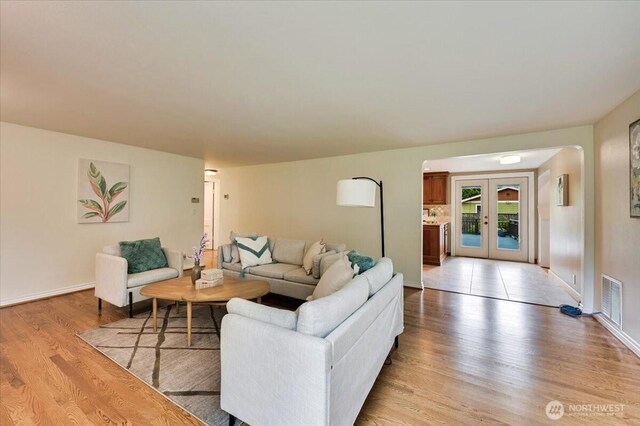 living room with light wood-style flooring, baseboards, and french doors