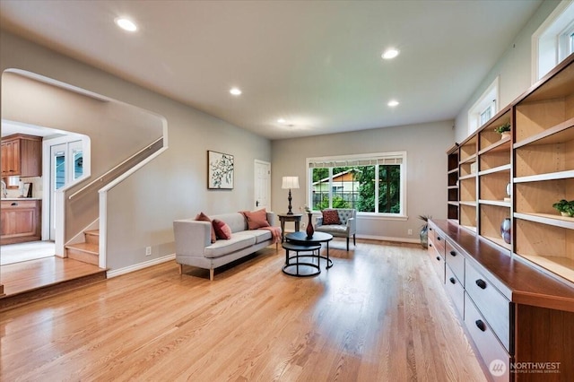 living area with light wood-type flooring, recessed lighting, baseboards, and stairway