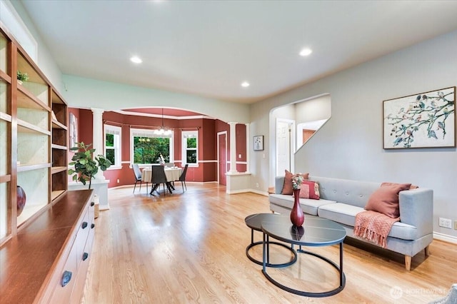 living area featuring ornate columns, arched walkways, light wood-style floors, baseboards, and recessed lighting