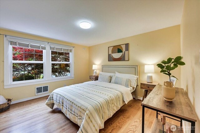 bedroom featuring multiple windows, wood finished floors, and baseboards