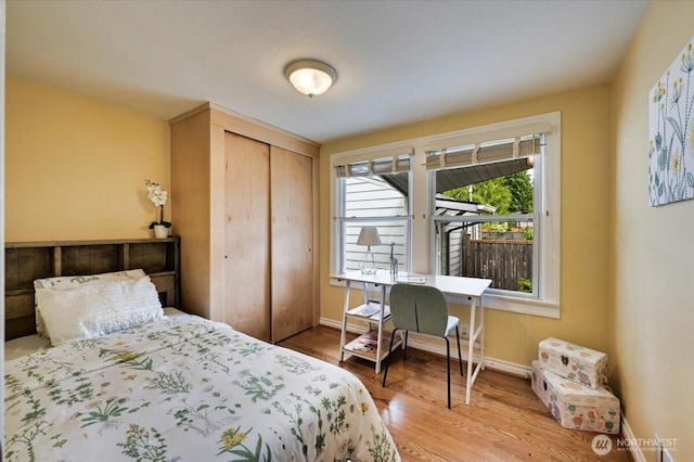 bedroom with a closet, wood finished floors, and baseboards