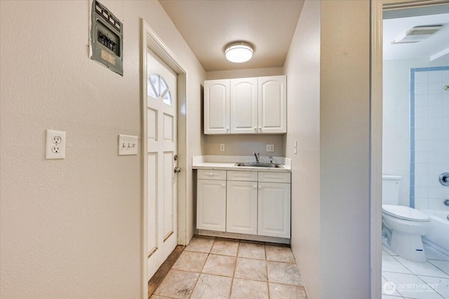 doorway to outside featuring a sink, a textured wall, and light tile patterned floors