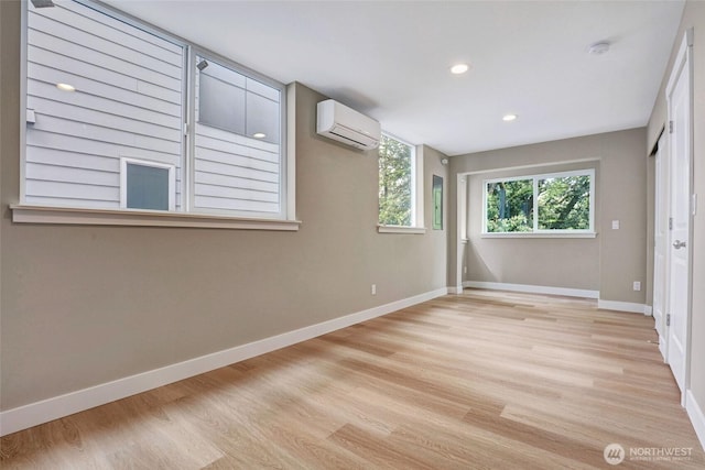 unfurnished bedroom featuring recessed lighting, wood finished floors, an AC wall unit, and baseboards