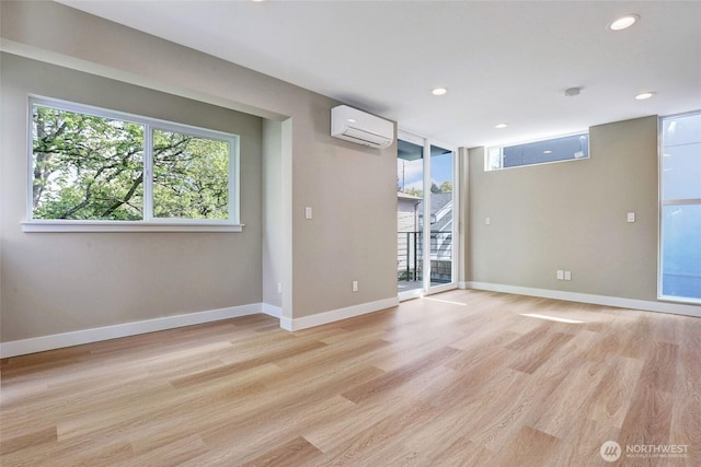 empty room featuring an AC wall unit, baseboards, light wood finished floors, and recessed lighting