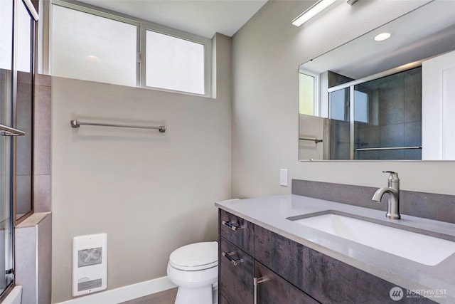 bathroom with toilet, vanity, a shower with door, and heating unit