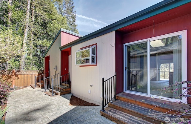 view of exterior entry with a patio area and fence