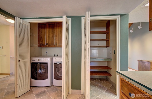 clothes washing area with washing machine and clothes dryer, baseboards, and cabinet space