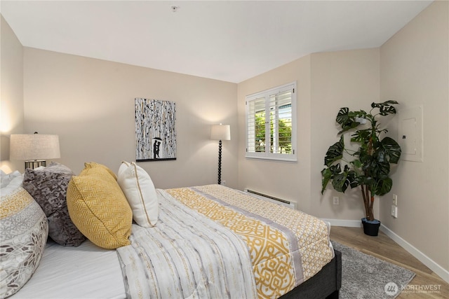 bedroom with baseboards, baseboard heating, and wood finished floors
