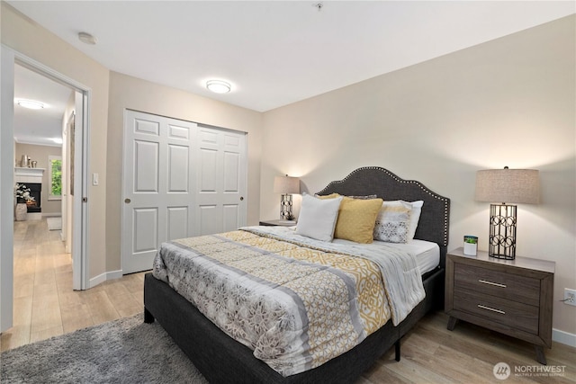 bedroom with baseboards, light wood-style flooring, and a closet
