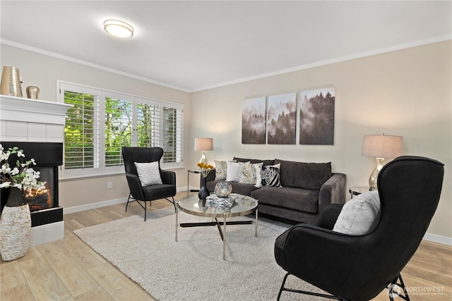 living room with crown molding, baseboards, a tiled fireplace, and wood finished floors