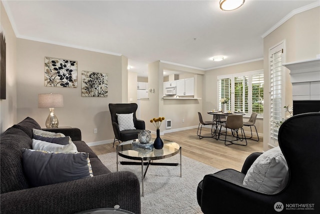 living area featuring light wood-style floors, ornamental molding, and baseboards