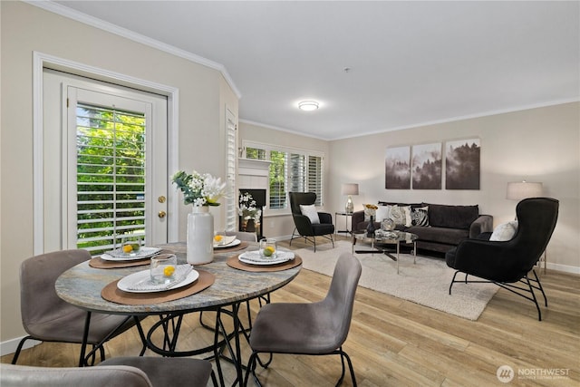 dining room featuring crown molding, light wood finished floors, and baseboards