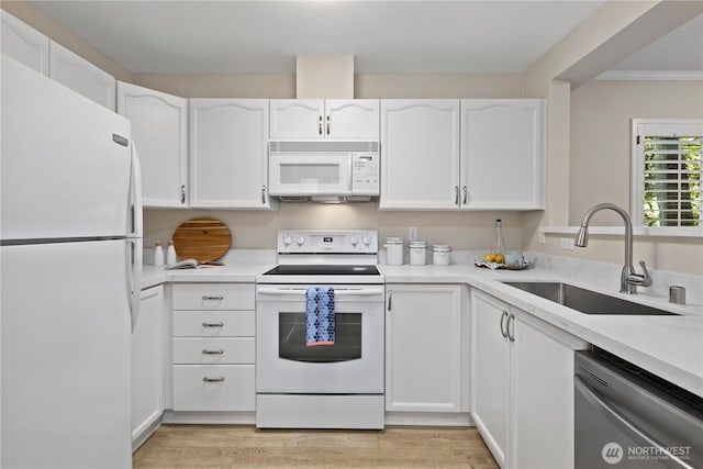 kitchen featuring white appliances, white cabinetry, a sink, and light countertops