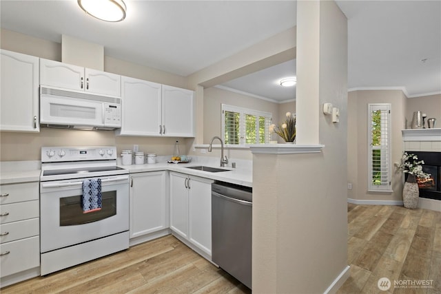 kitchen with crown molding, light wood-type flooring, a sink, white appliances, and white cabinetry