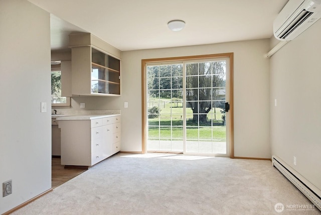 interior space with a baseboard heating unit, a wall mounted AC, baseboards, and light carpet